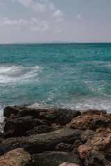 Rocky beach in Mallorca, in summer at high tide with the waves hitting and breaking on the coast.