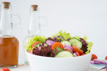 Summer vegetable salad with seasonal vegetables on rustic wooden background.