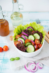 Summer vegetable salad with seasonal vegetables on rustic wooden background.