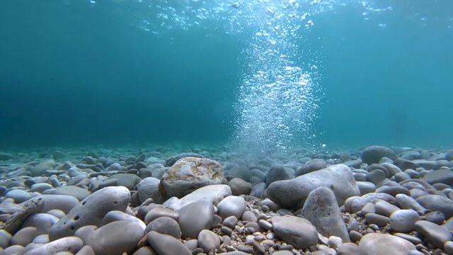 SLOWMO Underwater view of a clean sea with a rock falling in water