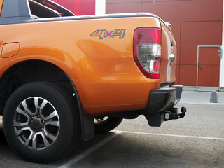 One orange all-terrain pick-up back part with trailer hitch in broad daylight