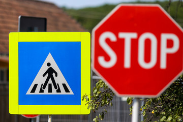 Stop and pedestrian crossing sign one next to another on a street