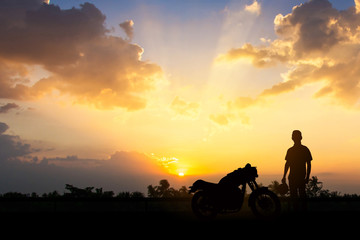 Fototapeta na wymiar Silhouette of Back biker or rider,motorbike parking with sunset background .Traveller man standing and holding helmet beside motorcycle.Trip and lifestyle of motorbike concept,copy space.