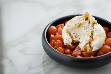 Burrata Büffelmozzarella Kugel mit Tomaten, Olivenöl und Balsamico auf schwarzen Teller