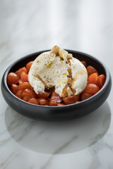 Burrata Büffelmozzarella Kugel mit Tomaten, Olivenöl und Balsamico auf schwarzen Teller