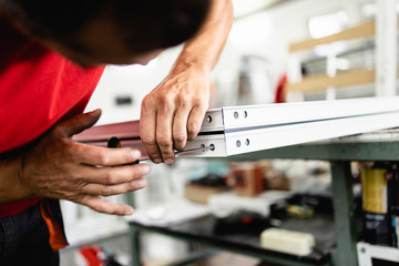 Manual worker assembling PVC doors and windows. Manufacturing jobs. Selective focus. Factory for aluminum and PVC windows and doors production.