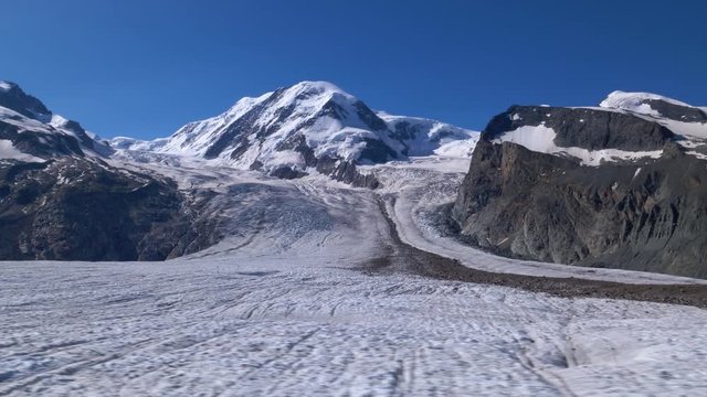 Aerial low fast sideways shot over the Gornergletscher glacier with Liskam summit in background. Zermatt area, Switzerland