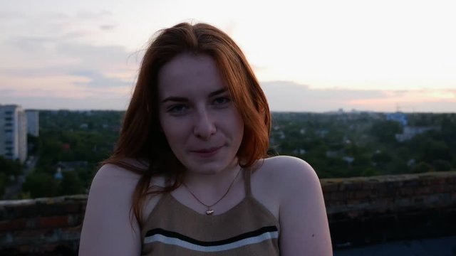 The redhead girl at sunset smiles seductively