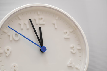Obraz na płótnie Canvas Clock face showing twelve o'clock with white background. White round wall clock. Twelve o'clock. Midday or midnight. 12 a.m. or 12 p.m