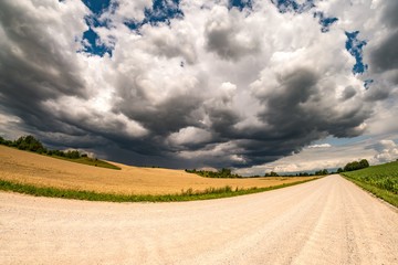 hdr panorama on asphalt road among fields in evening with awesome black clouds before storm