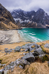 Kvalvika Beach - Lofoten Islands, Norway, Europe. Beautiful white-sand Arctic Beach with rocks surrounded by mountains before the storm