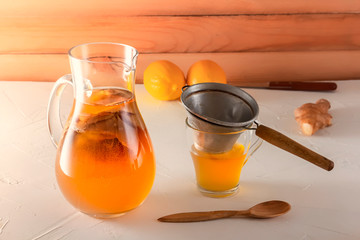 Homemade fermented drink Kombucha in a glass jar with lemon and ginger on a wooden table. Copy space