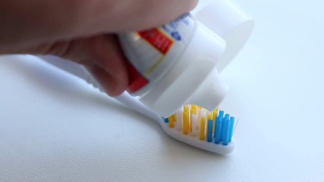 Hand spreading toothpaste on a toothbrush