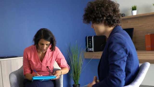 Businesswoman talking with young man during job interview at office