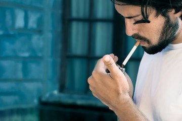 Modern young man with beard he lights a cigarette, toning