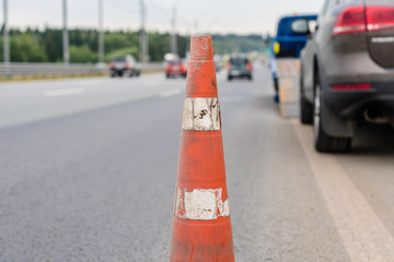 Attention traffic cone on the road. Selective focus. Tow truck towing a broken down car on the highway
