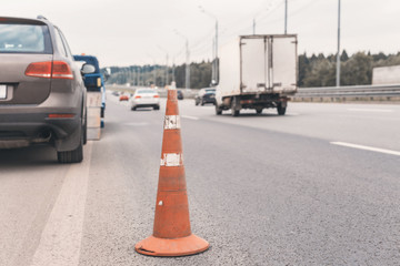 Attention traffic cone on the road. Selective focus. Tow truck towing a broken down car on the...
