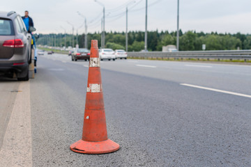 Attention traffic cone on the road. Selective focus. Tow truck towing a broken down car on the...