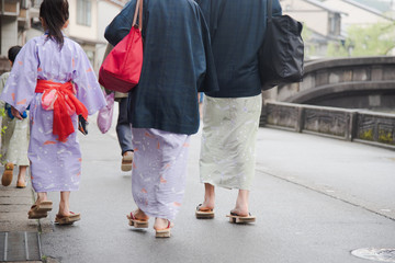 Japanese family wearing yukata or kimono and walking at Kinosaki Onsen village street in Toyooka...
