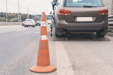 Attention traffic cone on the road. Selective focus. Tow truck towing a broken down car on the highway