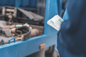 Man pays paper money for tow truck to worker towing a broken down car. Selective focus. Concept