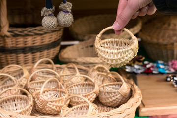 little straw woven baskets in a large basket. A human hand picks up one of the baskets. Souvenirs...
