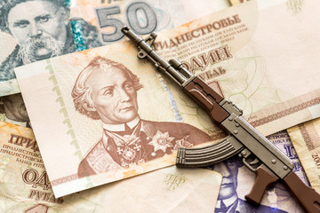 various transnistrian ruble banknotes and kalashnikov ak47 assault rifle war conflict concept