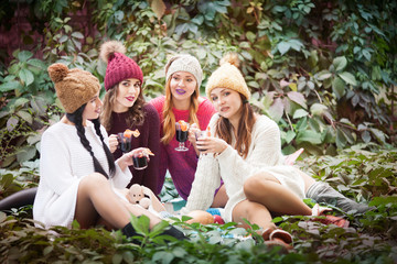 Young women drink mulled wine in autumn park. Sunny autumn day.