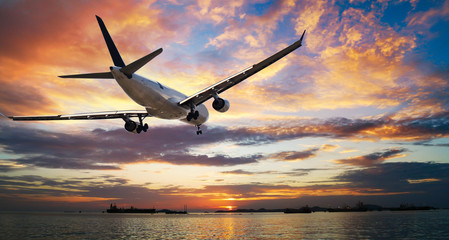 Airplane in the sunset sky flight travel transport airline background concept.