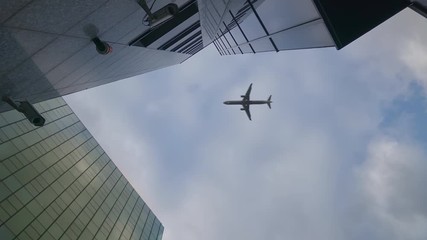 Airplane flying over skyscrapers and reflects in glass modern facades, Germany