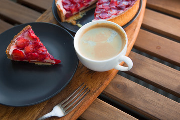 Still life with a Cup of coffee and sweet dessert with strawberries on a wooden table,