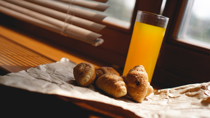 Obraz na płótnie Canvas Freshly baked croissants with orange juice on kraft paper. Closeup photography of fresh delicious dessert for breakfast.