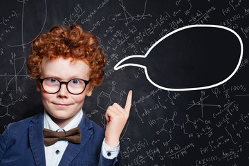 Successful child boy and empty speech clouds bubbles on chalkboard background