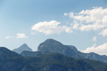 Beautiful landscape in the mountains. Lovely view of the Taurus Mountains against the blue sky and clouds. Soft sunlight falls on the mountain tops. Kemer, Turkey. Postcard view