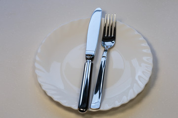 Empty plate with steel fork and knife.