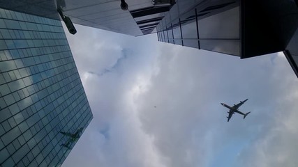 Airplane flying over skyscrapers and reflects in glass modern facades, Germany