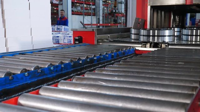Industrial and machinery concept. A tecnological part of bearing production and assembling. Conveyor in bearing factory. Ready items on moving technology line after are being poured with engine oil