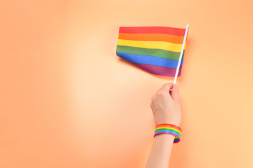 LGBT flag in woman hand on orange background. Copy space.