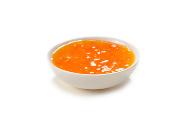 Orange sauce in white plate on white background.