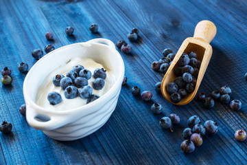 fresh tasty blueberry with natural yoghurt on wooden background