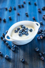 Obraz na płótnie Canvas fresh tasty blueberry with natural yoghurt on wooden background