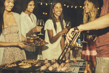 Group of friends making barbecue in the backyard at dinner time