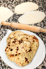Preparing homemade Naan, indian or asian bread. Preparation process, dough on kitchen table and delicious breads ready to eat. Copy space top.