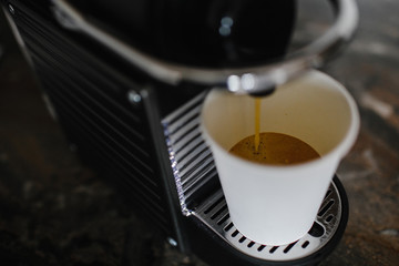 Black coffee machine pouring espresso into cup. 