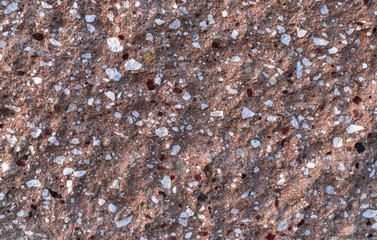 Isolated closeup of rough textured brown and sand colored block with red white and black chips background