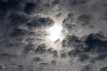 Dark clouds make the sky black, sun in the centre. Before rain clouds.
