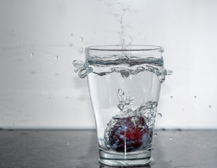 Frucht fällt in das Glas mit Wasser