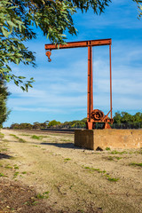 Old crane next to railway line used for loading cargo onto trains in rural Australia 
