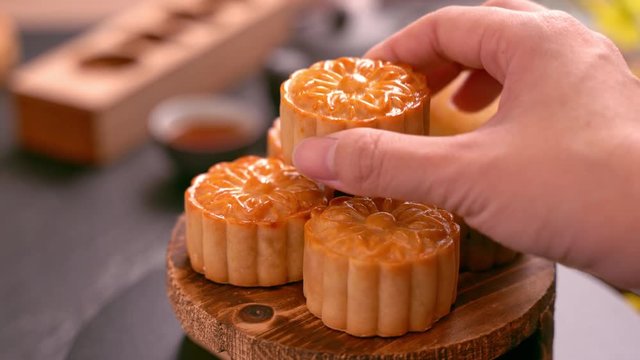 Woman taking beautiful moon cake pastry to eat and share with family to celebrate Mid-Autumn Festival. Reunion event concept.