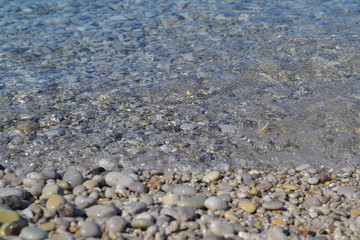 Sea stones in the sea water. Pebbles under water. The view from the top. Nautical background. Clean sea water. Transparent sea.